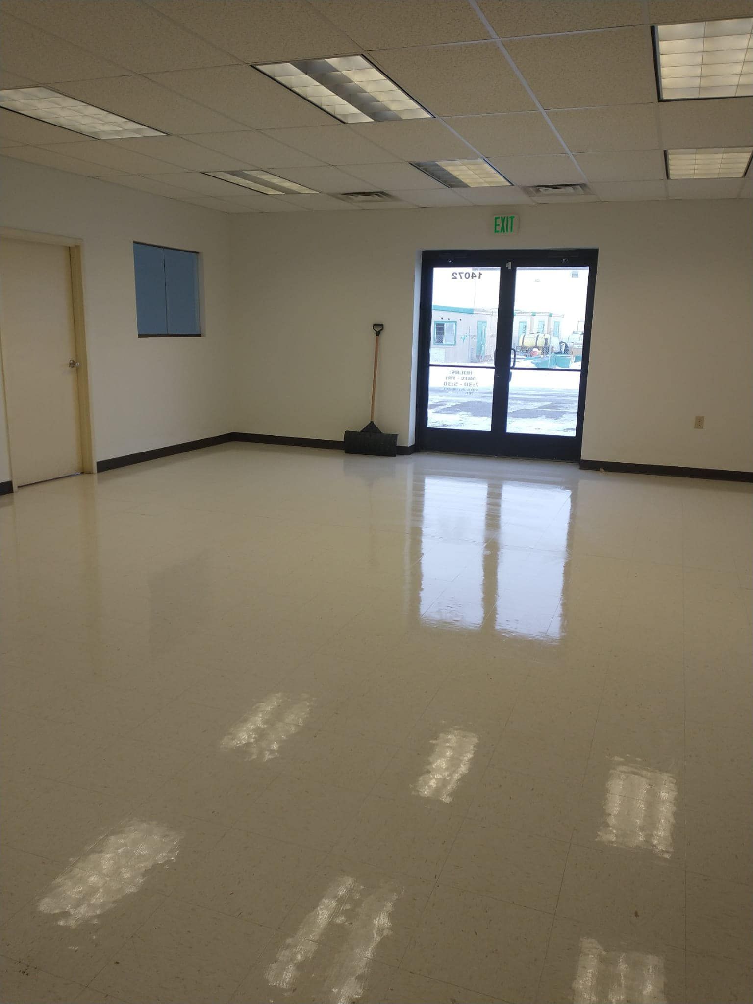 Empty room with glossy floor, double doors, and overhead lights.