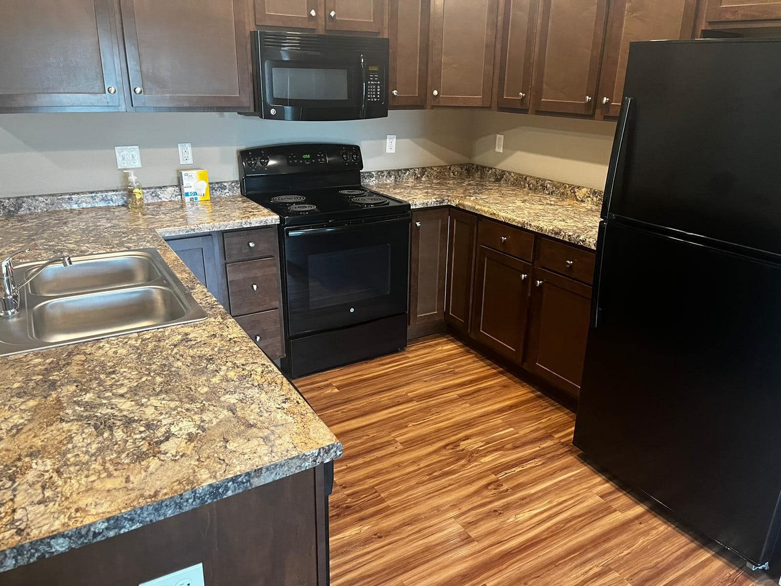 Kitchen with brown cabinets, black appliances, and countertops.