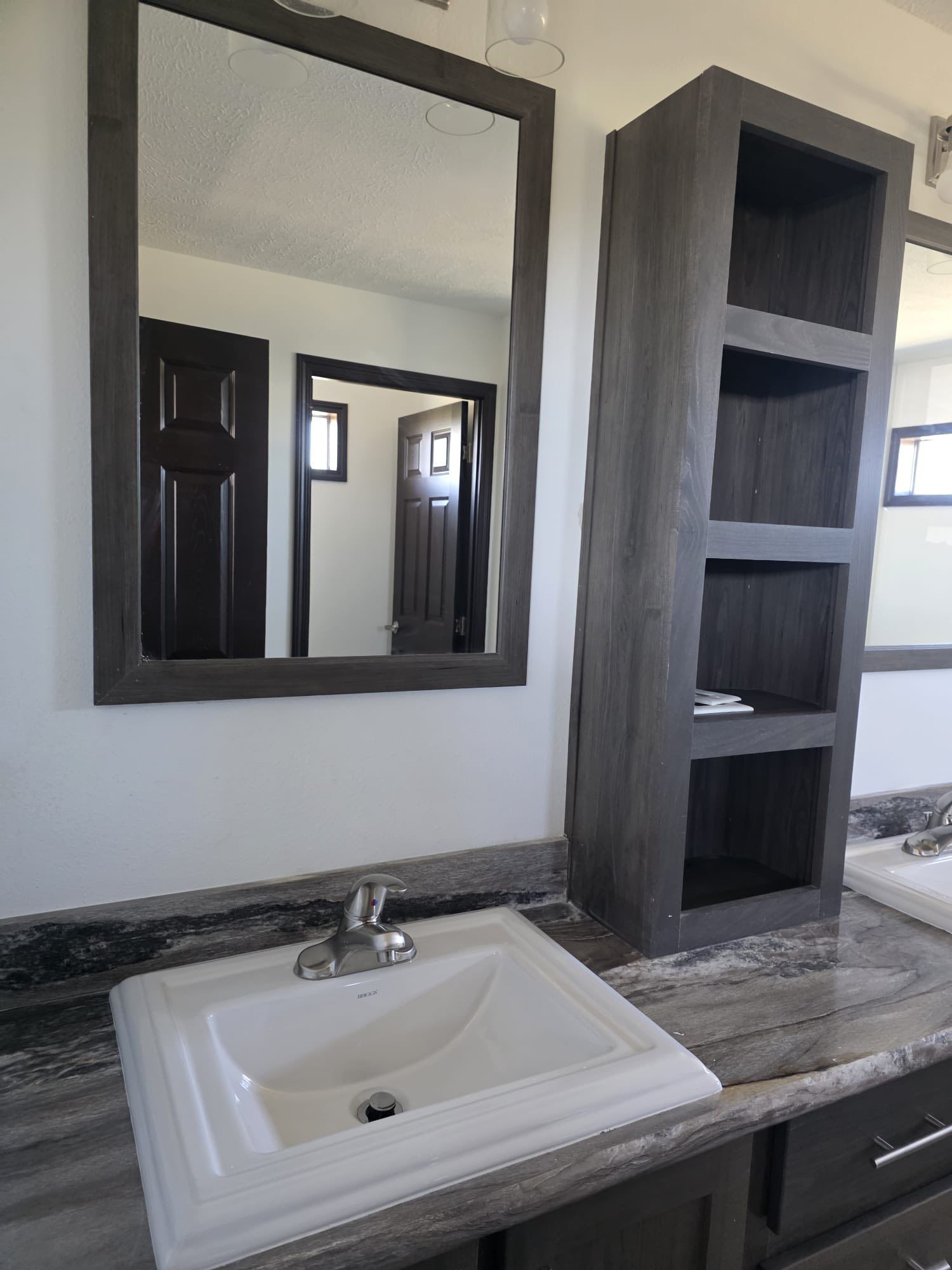 Bathroom with a vanity, mirror, sink, and open shelving in neutral tones.