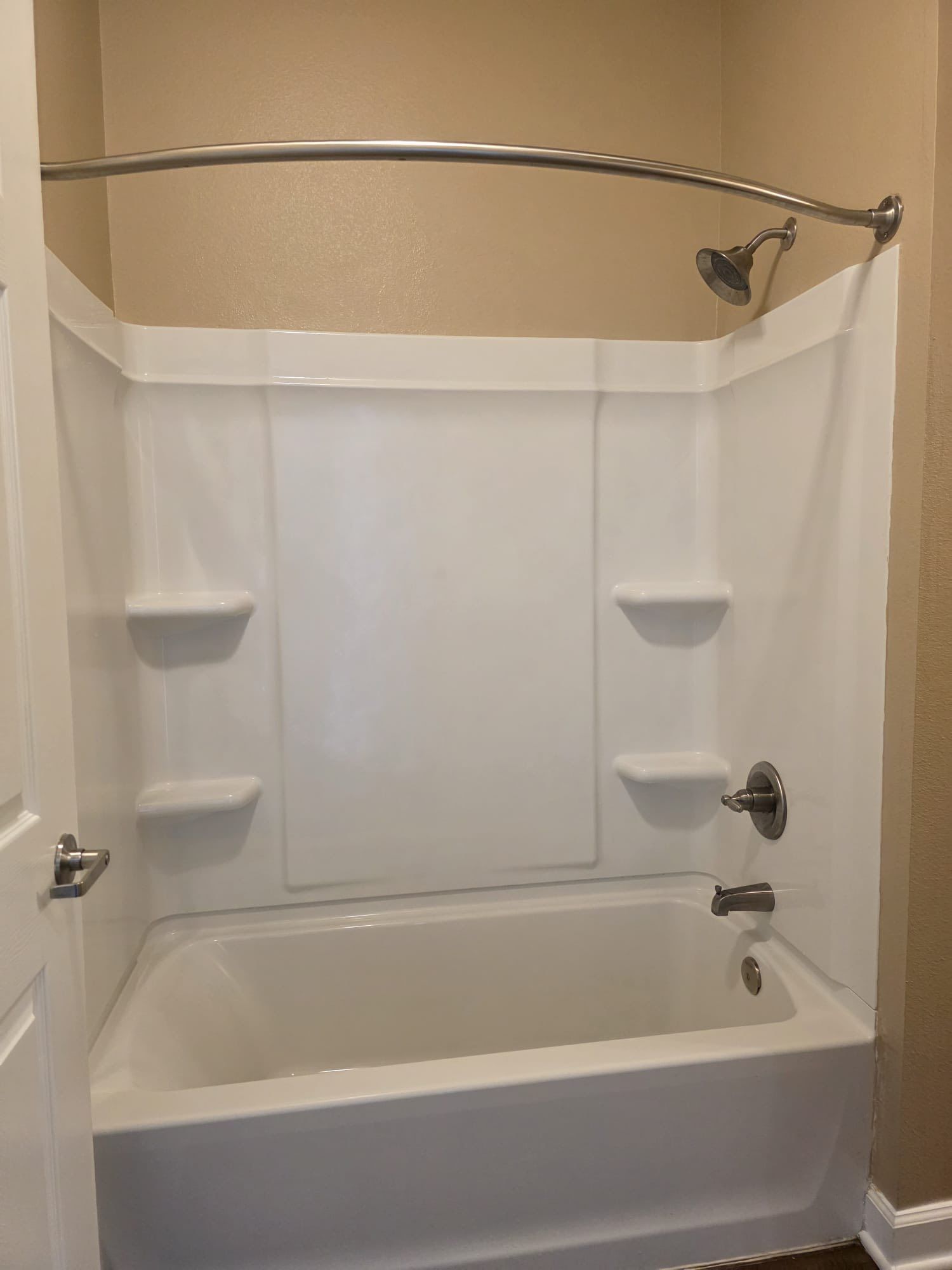 White bathtub and shower combo in a bathroom with silver fixtures.