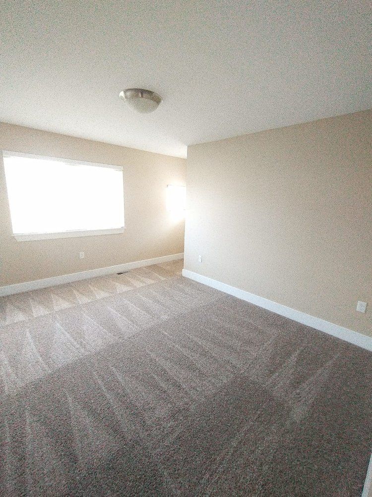 Empty room with tan walls, light carpet, and a window.