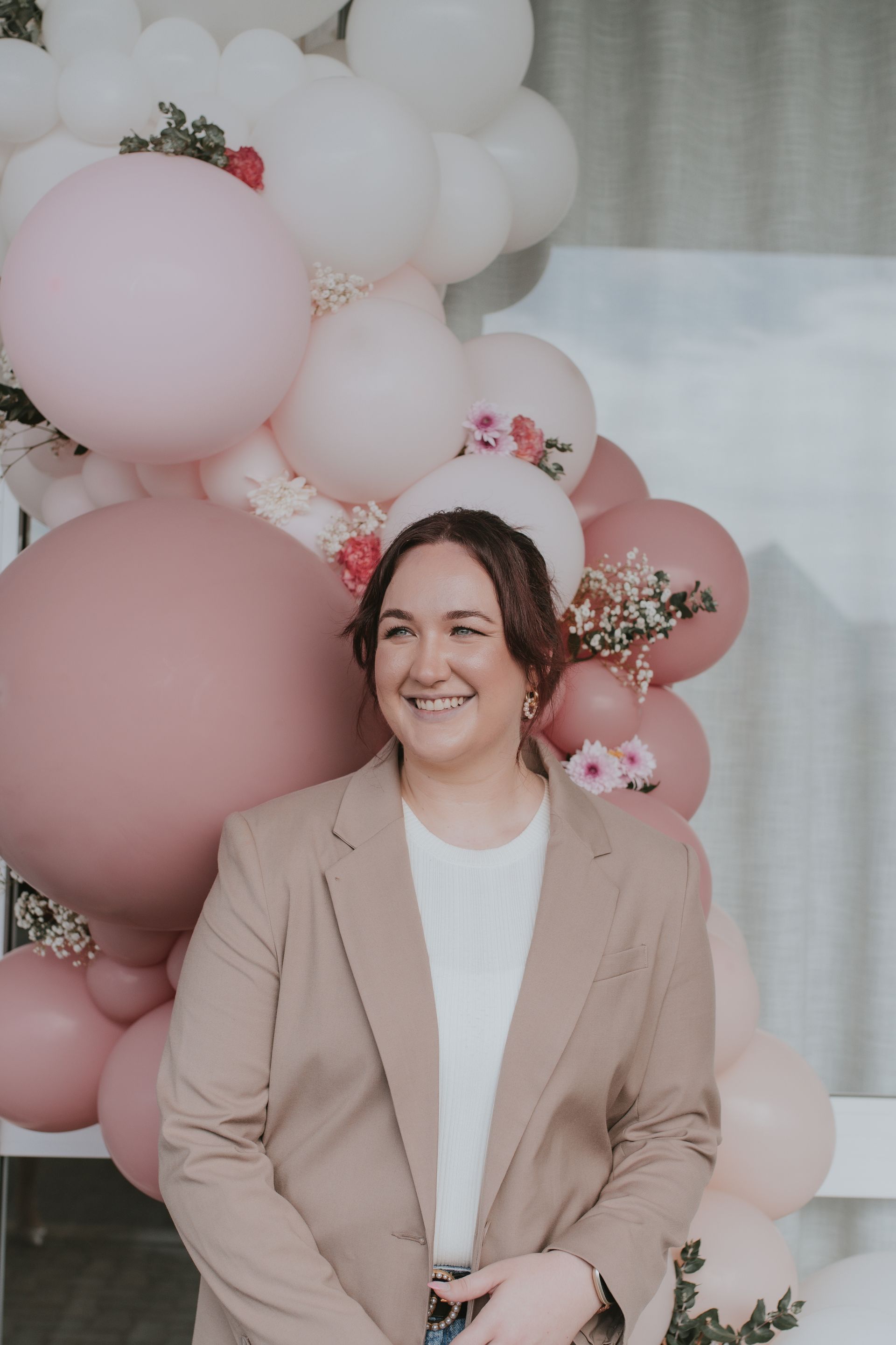 A Woman With Long Hair Is Smiling And Holding Her Hair — Bloom Skin Brows & Beauty In Bungalow, QLD