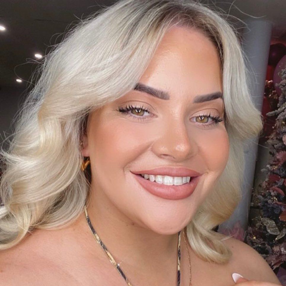 A Woman With Blonde Hair And A Necklace Is Smiling In Front Of A Christmas Tree — Bloom Skin Brows & Beauty In Bungalow, QLD
