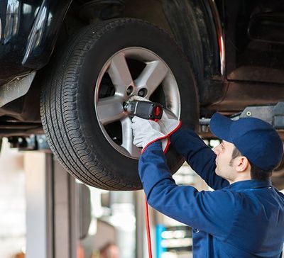Vehicle Inspection— Portrait Of A Mechanic Replacing Wheel in Fairfield, OH