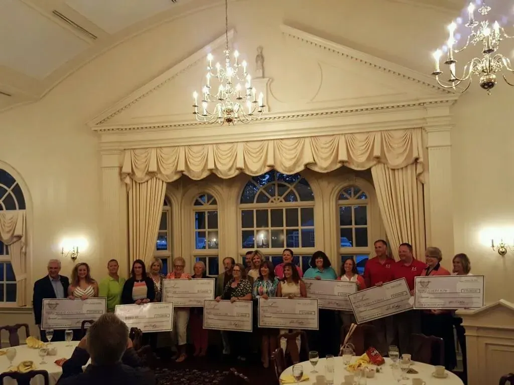 A group of adults holding large checks.