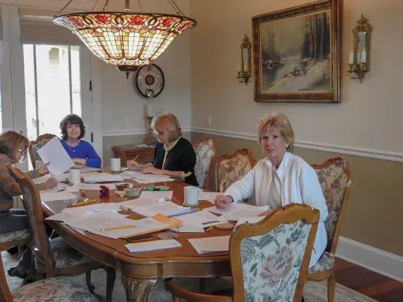 A group of women are sitting around a table in a dining room.
