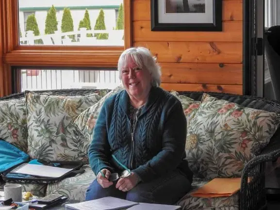 A woman is sitting on a couch writing in a notebook.