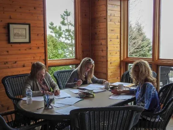 A group of women are sitting around a table in a cabin.