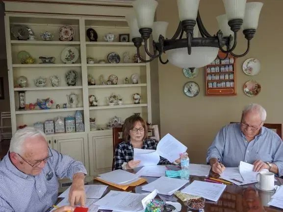 A group of people are sitting at a table looking at papers.