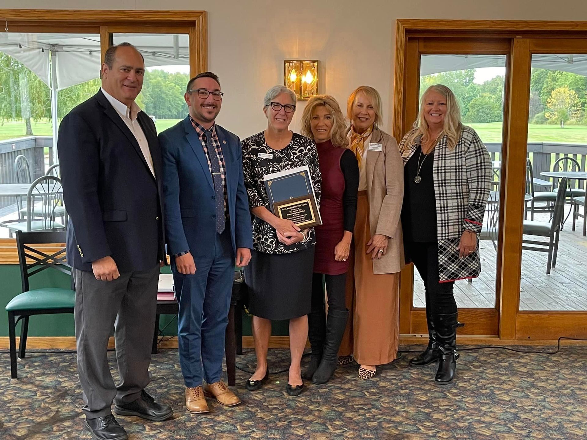 A group of people posing for a picture with one woman holding an award.