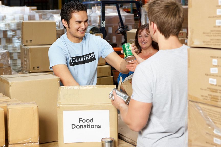 A man in a volunteer shirt holds a can of food.