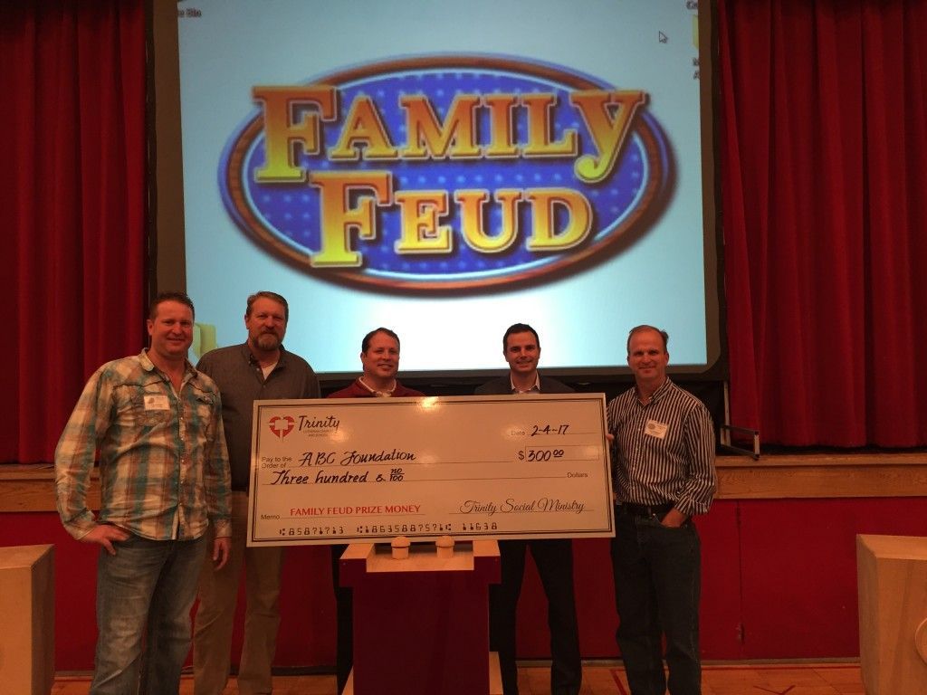 A group of people standing in front of a Family Feud logo with a large check.
