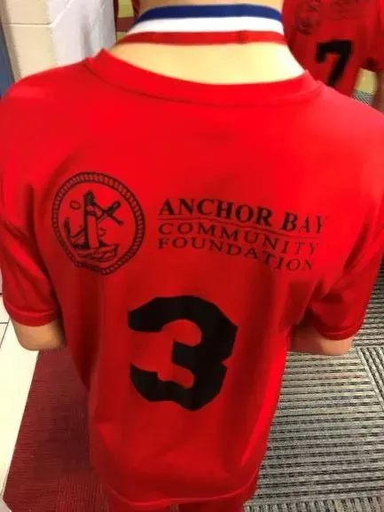 A kid wearing an Anchor Bay Community Foundation shirt.