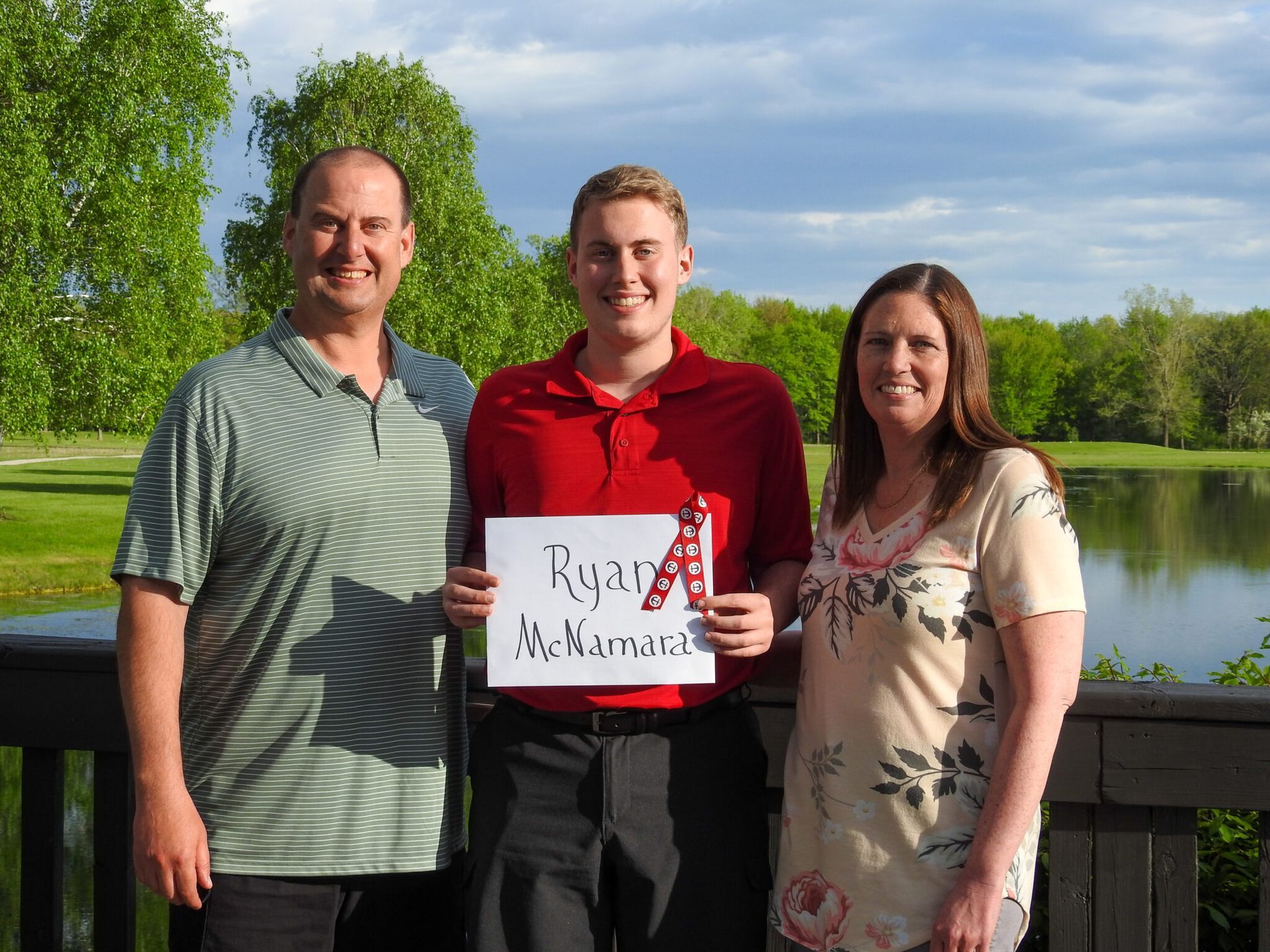 A young man holding a sign with his name on it.