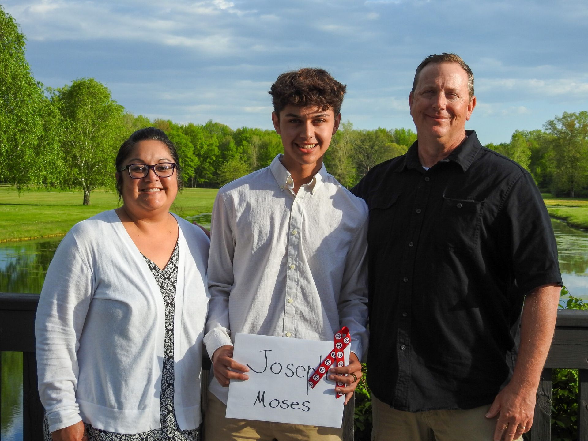 A young man holding a sign with his name on it.