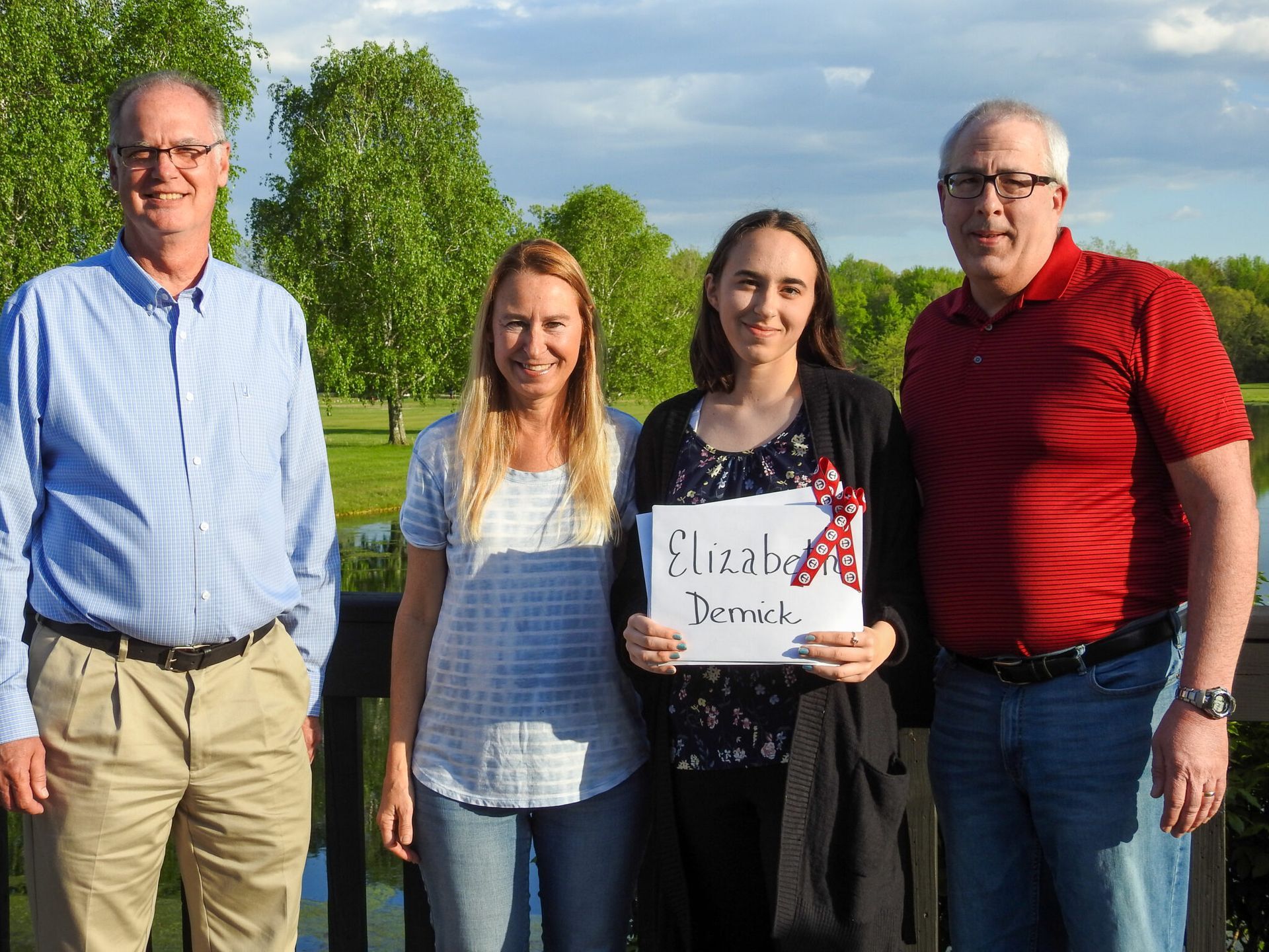 A young woman holding a sign with her name on it.