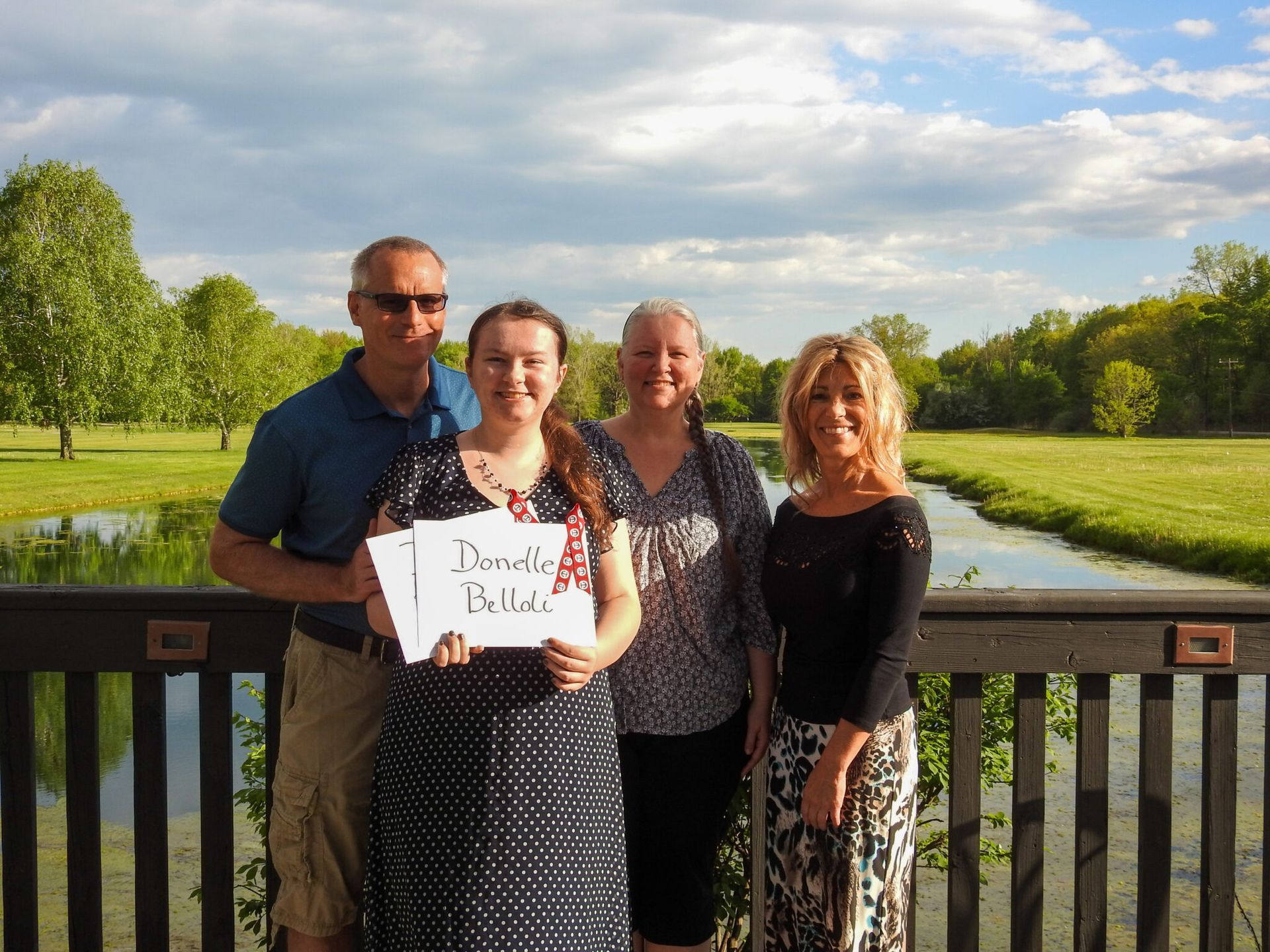 A young woman holding a sign with her name on it.
