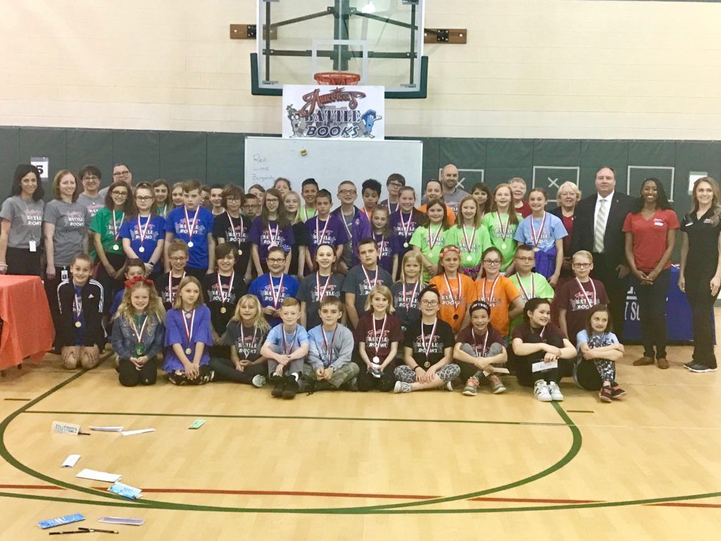 A group of kids are posing for a picture in front of a sign that says
