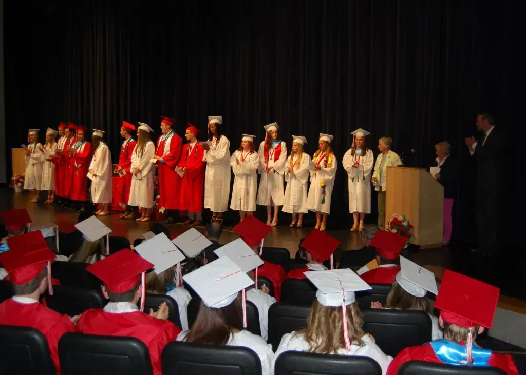 A group of graduates are lined up on a stage.