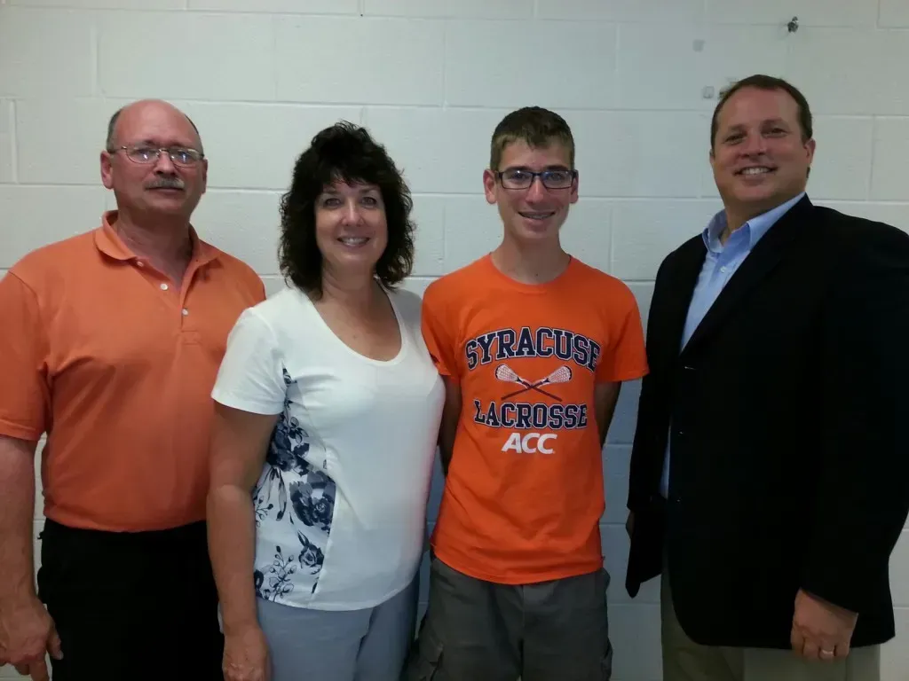 A boy wearing an orange Syracuse Lacrosse shirt.