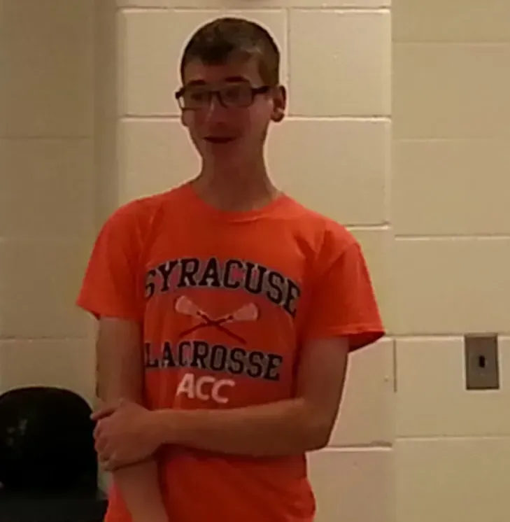 A boy wearing an orange Syracuse Lacrosse shirt.