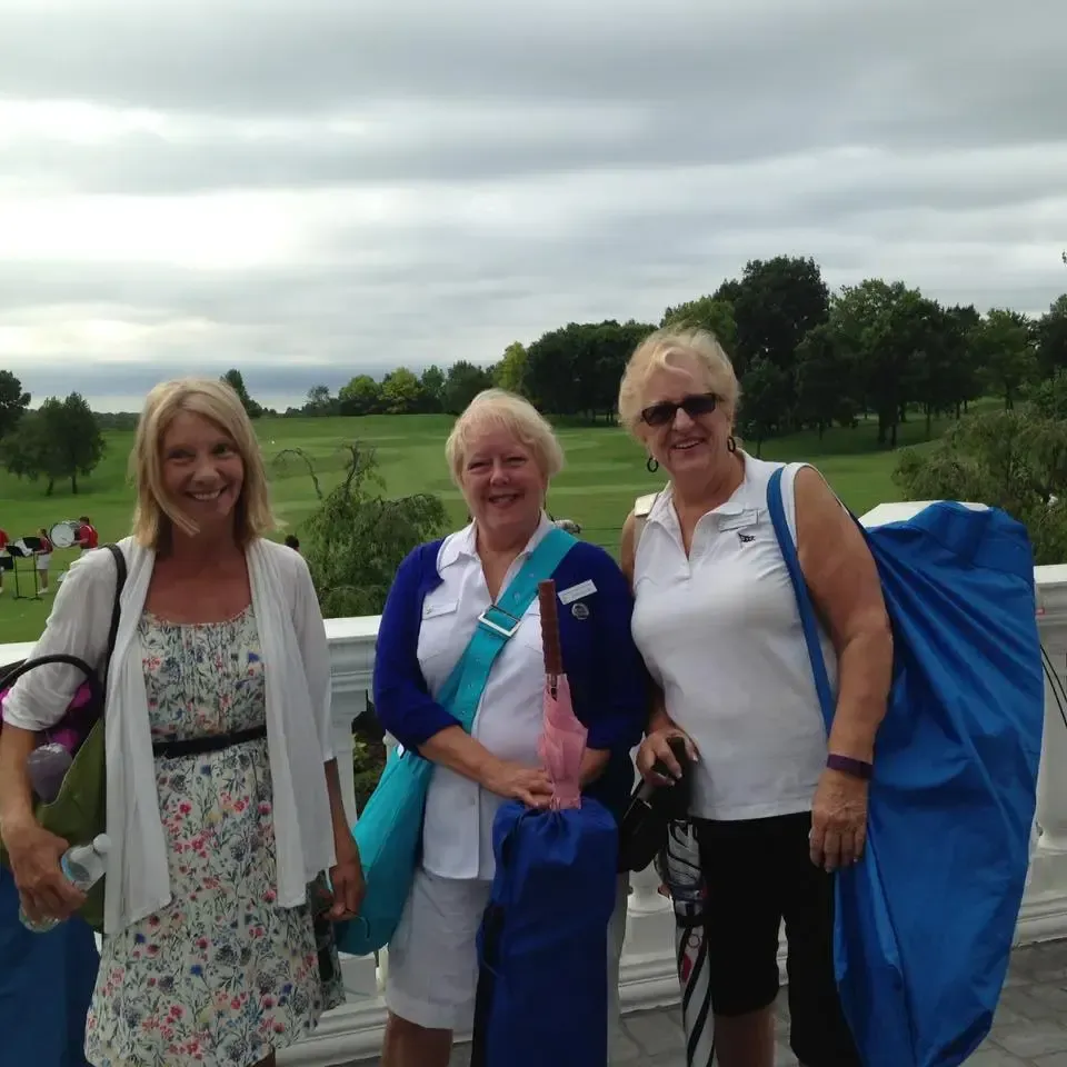 A group of women outside carrying bags full of equipment.