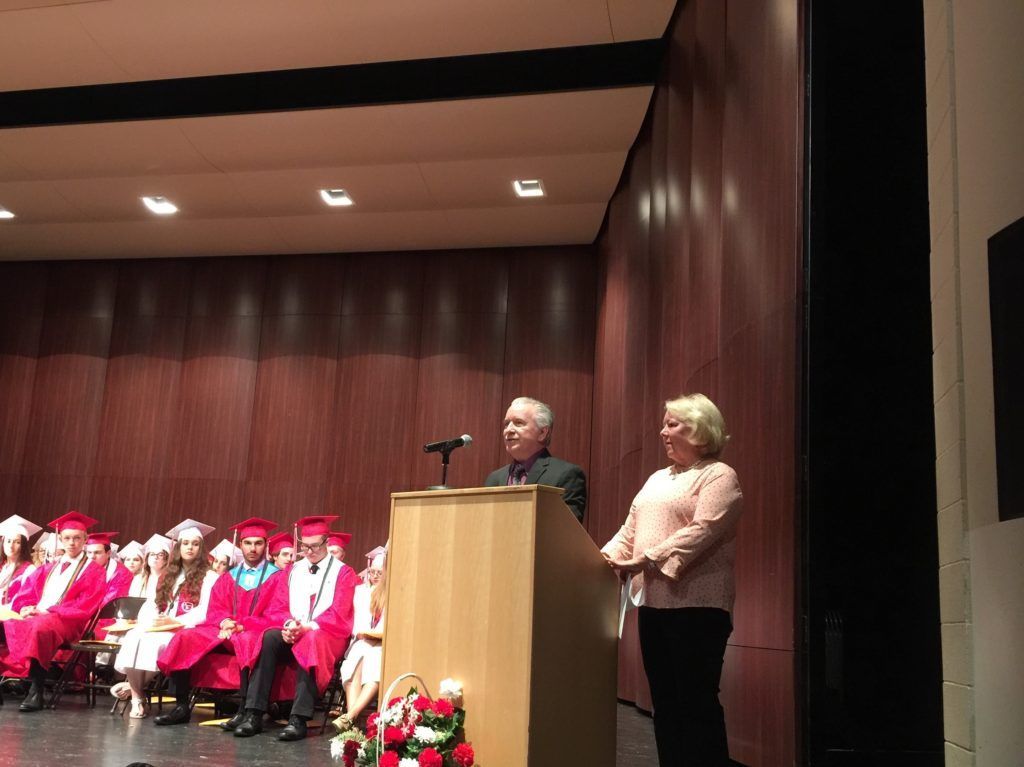 A man standing behind a podium in front of a group of graduates.