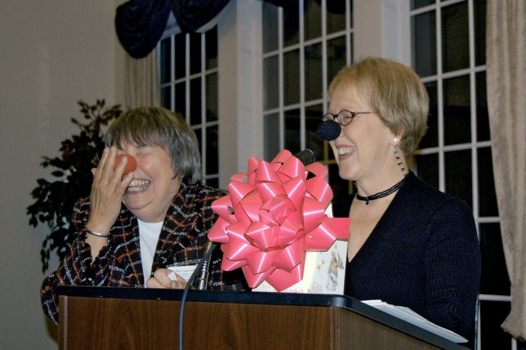 Two women with fake reindeer noses laughing.