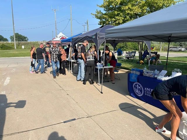 People gathered at outdoor event with tents and tables.