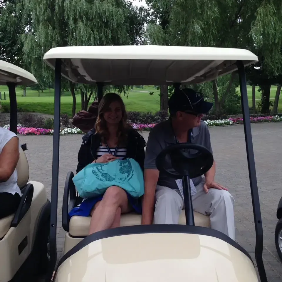 Two young adults sit in a golf cart.