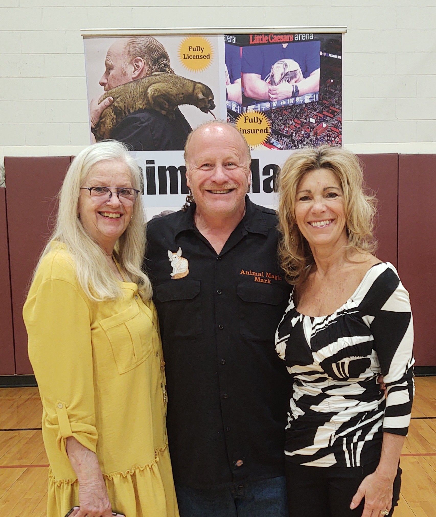 A man in an Animal Rescue shirt poses with two women.