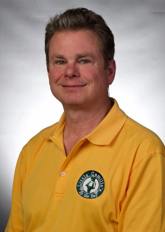 A man wearing a yellow shirt with a green logo on it.