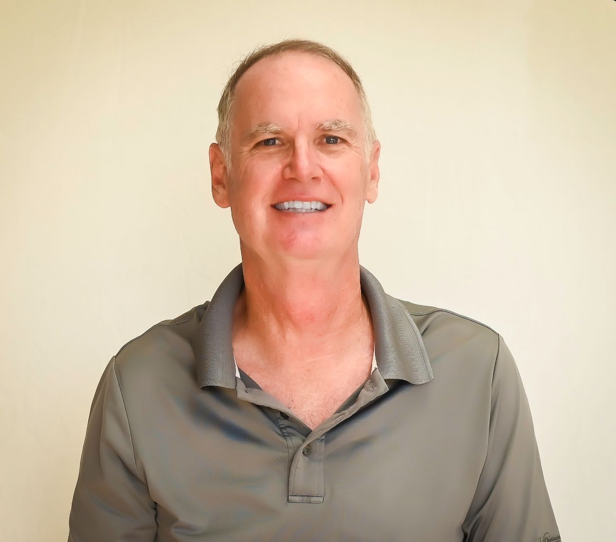 A man in a grey shirt is smiling for the camera.