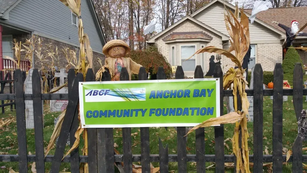 An Anchor Bay Community Foundation sign on a black fence.