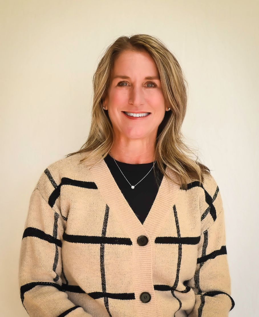 A woman in a plaid sweater is smiling for the camera.