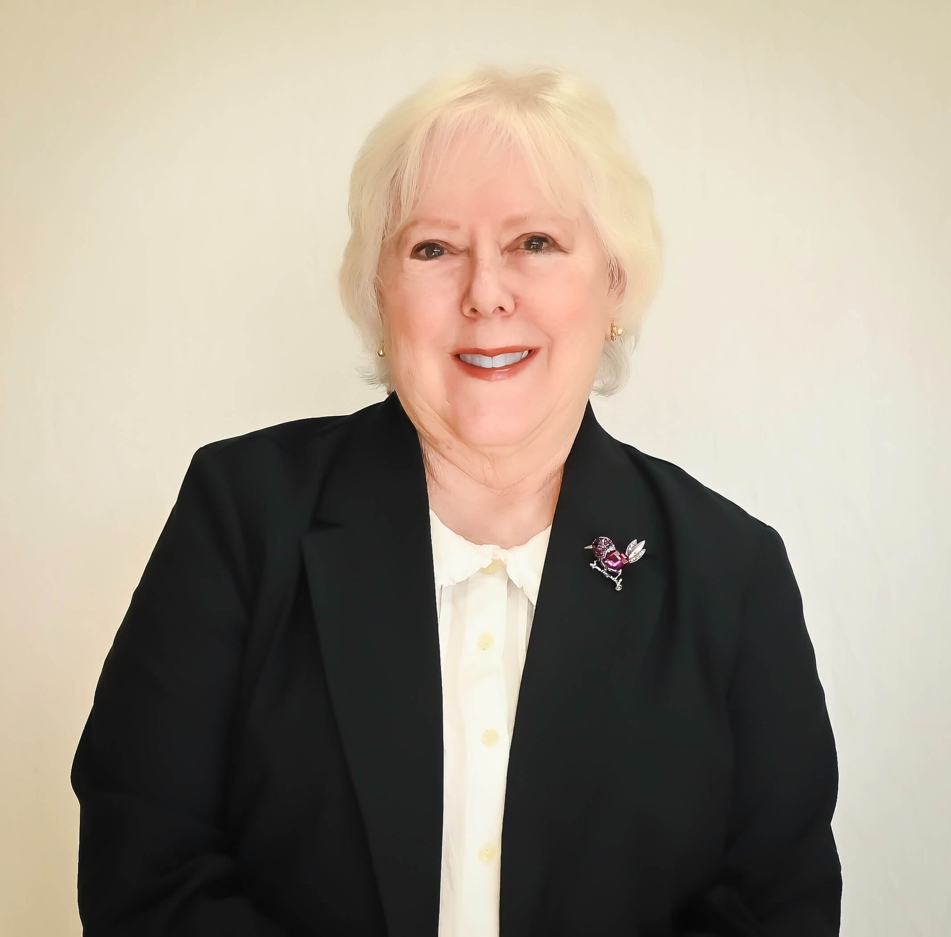 A woman wearing a black jacket and white shirt is smiling for the camera.