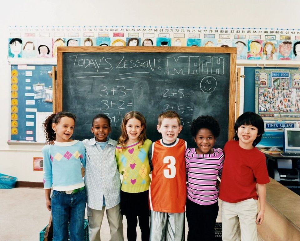 A group of children standing in front of a chalkboard that says today 's lesson: math.