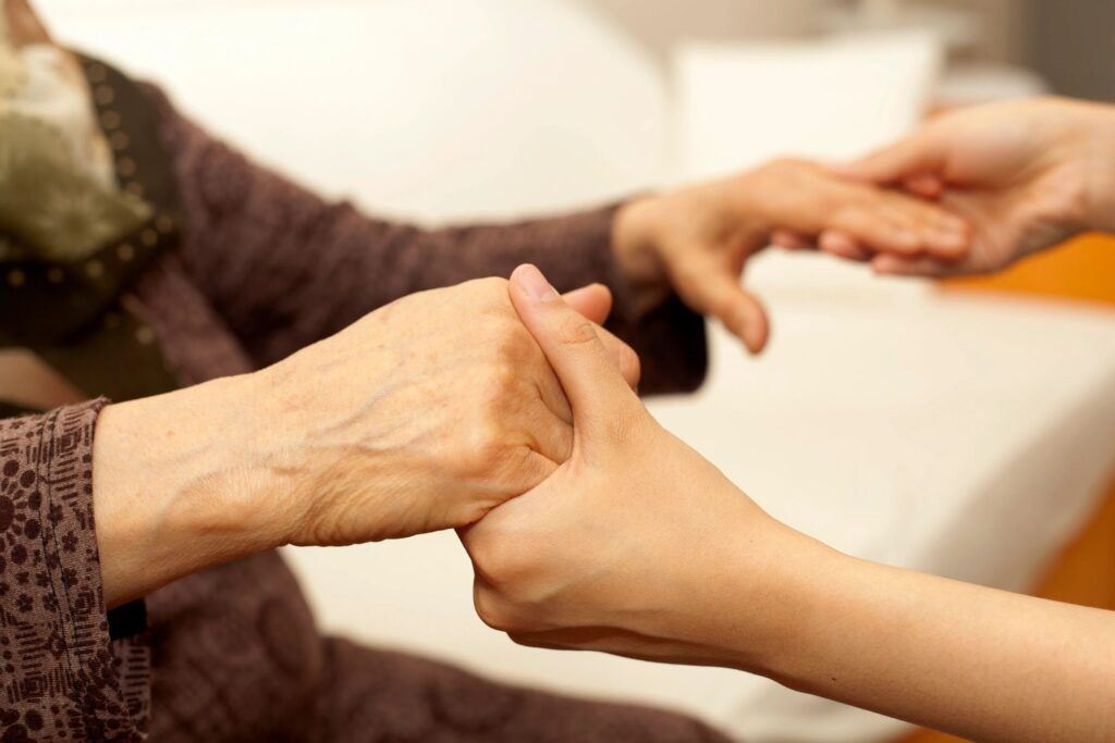 A woman is holding the hand of an older woman.