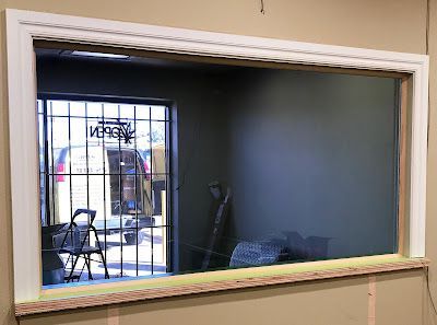 A large window in a room with a reflection of a van in the window.