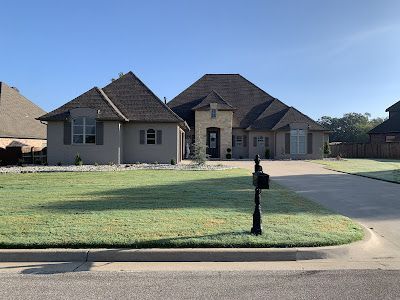 A large house with a lush green lawn and a mailbox in front of it.