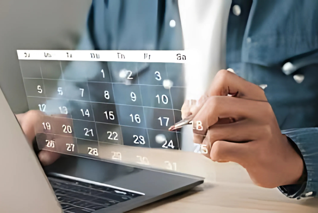 A man is looking at a calendar on a laptop computer.