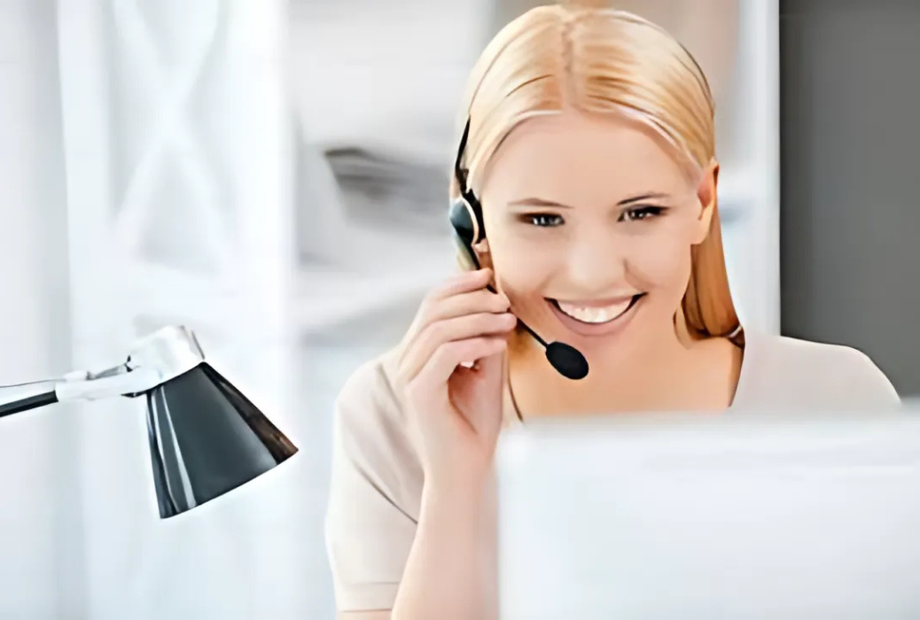 A woman wearing a headset is sitting in front of a laptop computer.