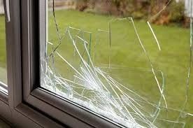 A close up of a broken glass window with a green background.