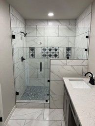 A bathroom with a walk in shower and a sink.