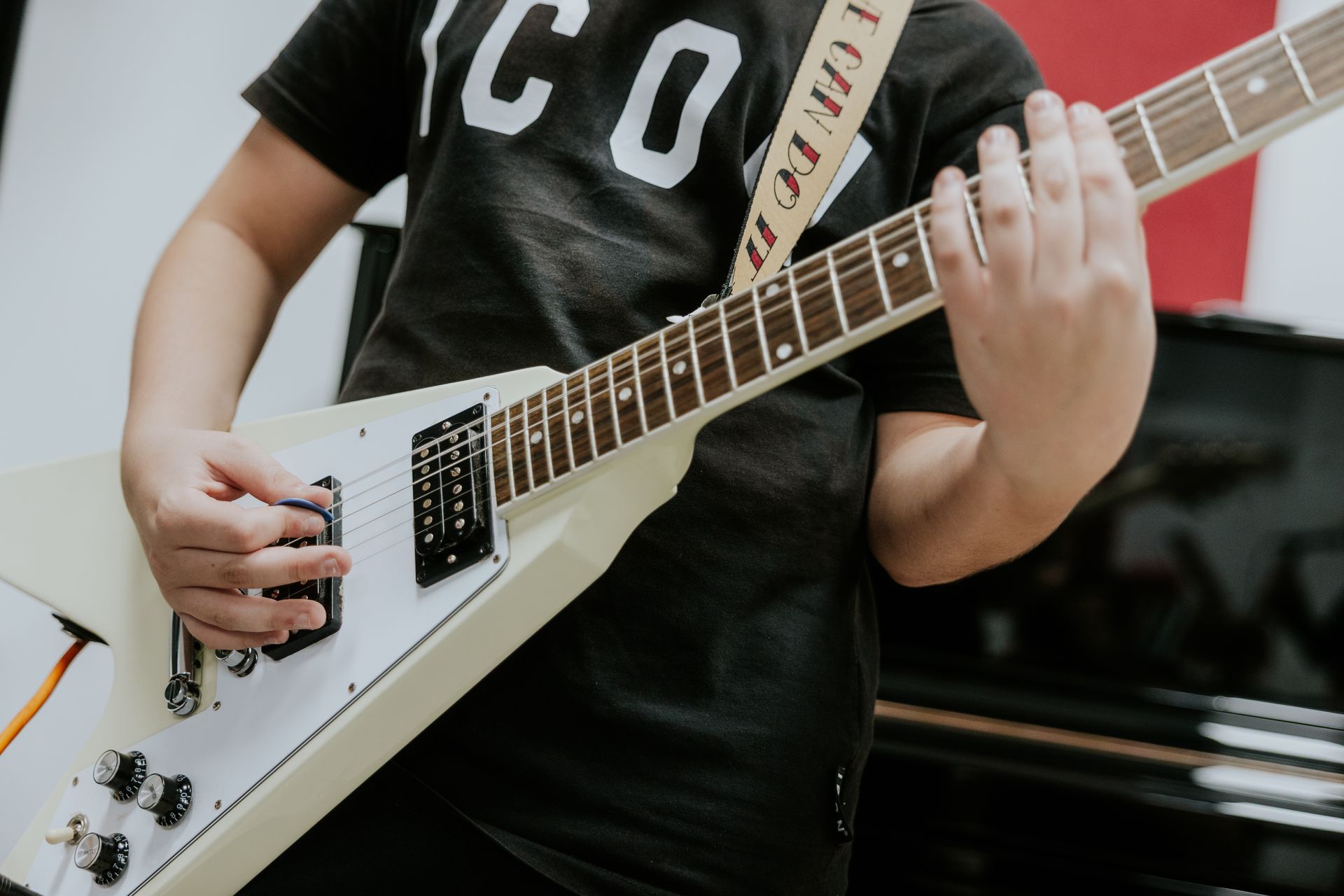 Persona che suona un basso elettrico nero, in un ambiente chiuso.