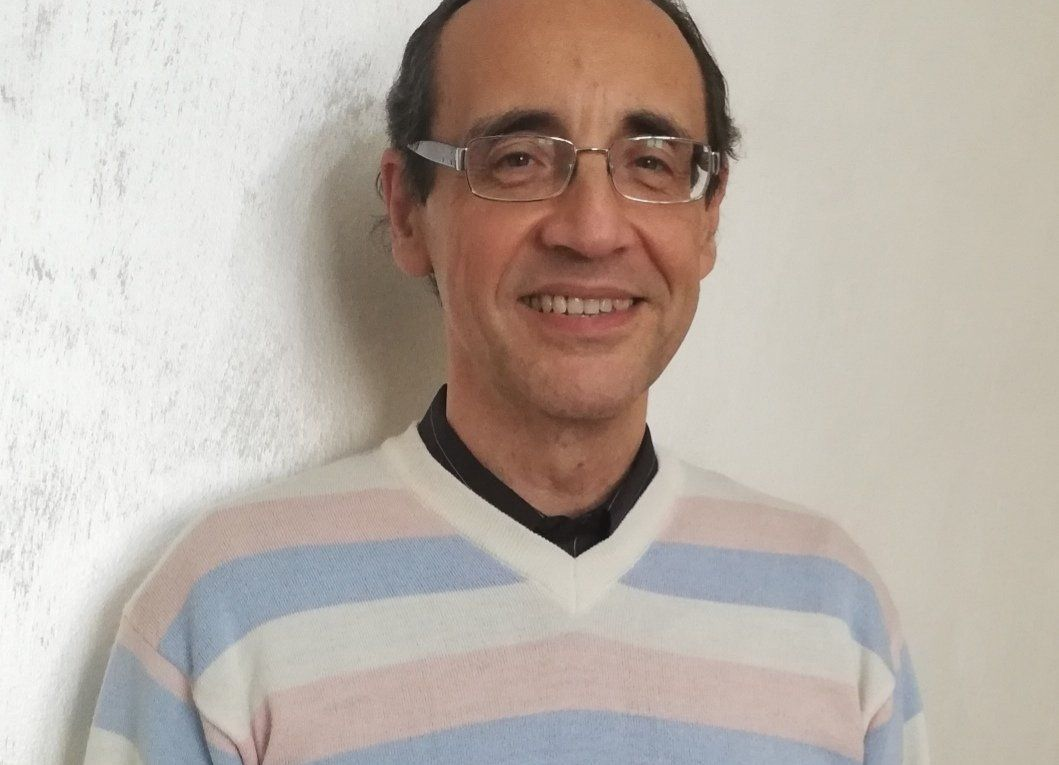 Uomo sorridente con occhiali e maglione a righe.