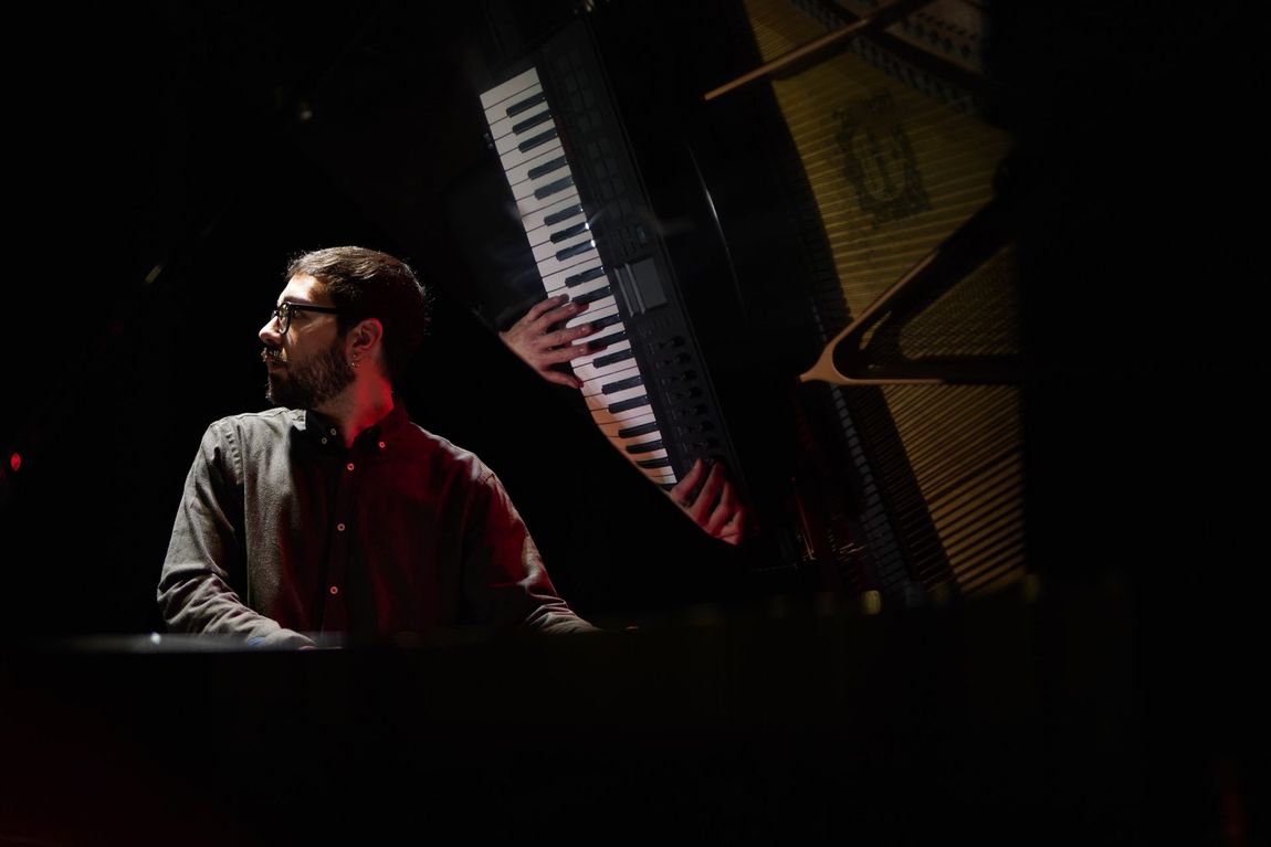 Un uomo suona la tastiera, il palco è scarsamente illuminato.