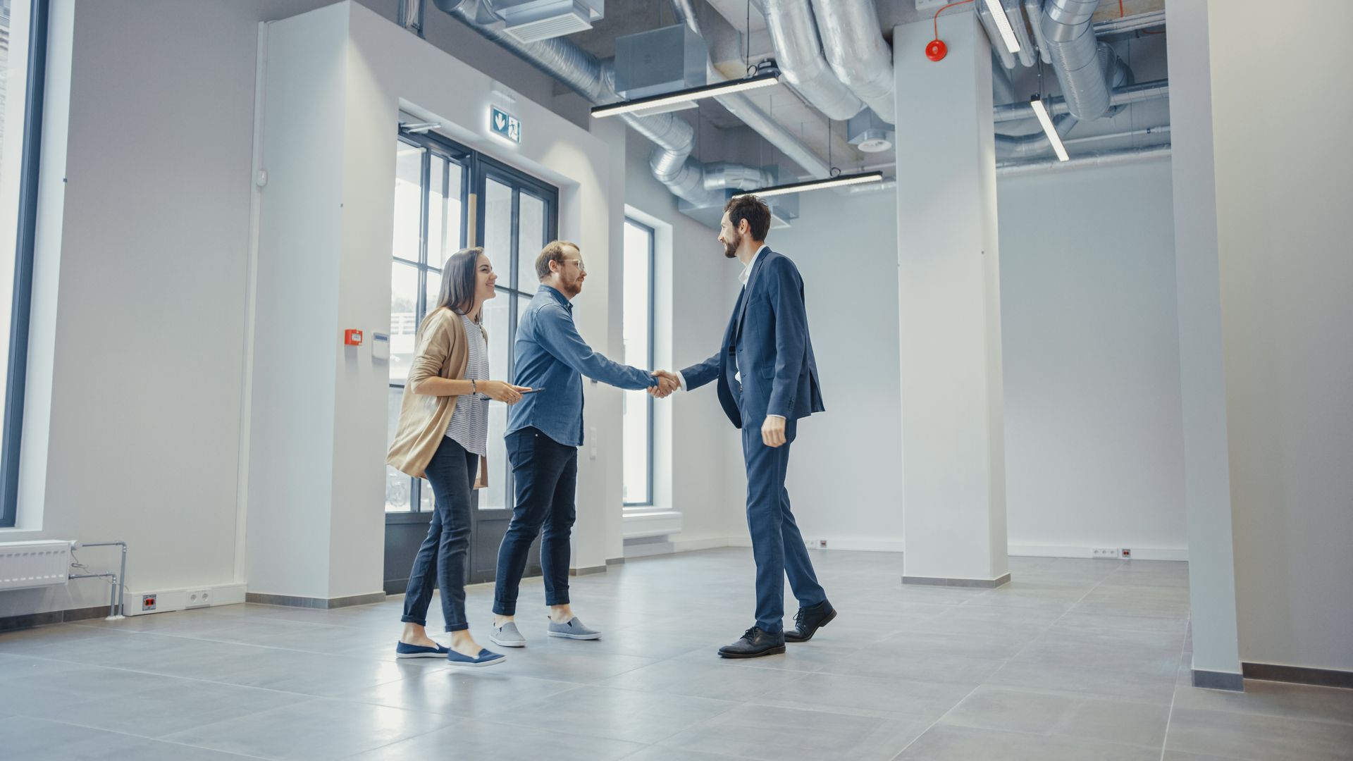 Professional real estate showing in a spacious office with a client and agent handshake.
