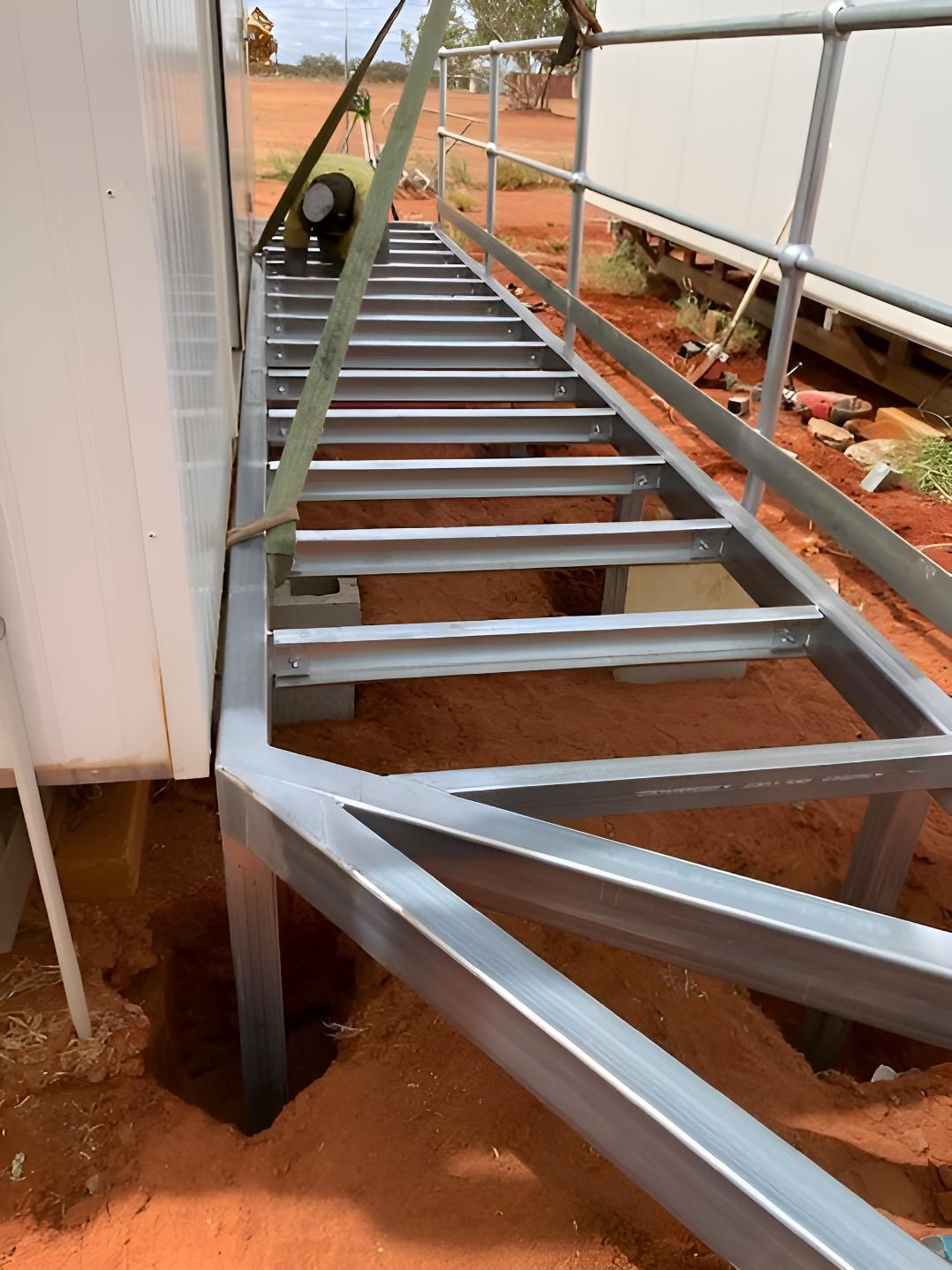 A Metal Staircase Is Being Built Next To A Building — Alice Sheds & Structures In Ciccone, NT