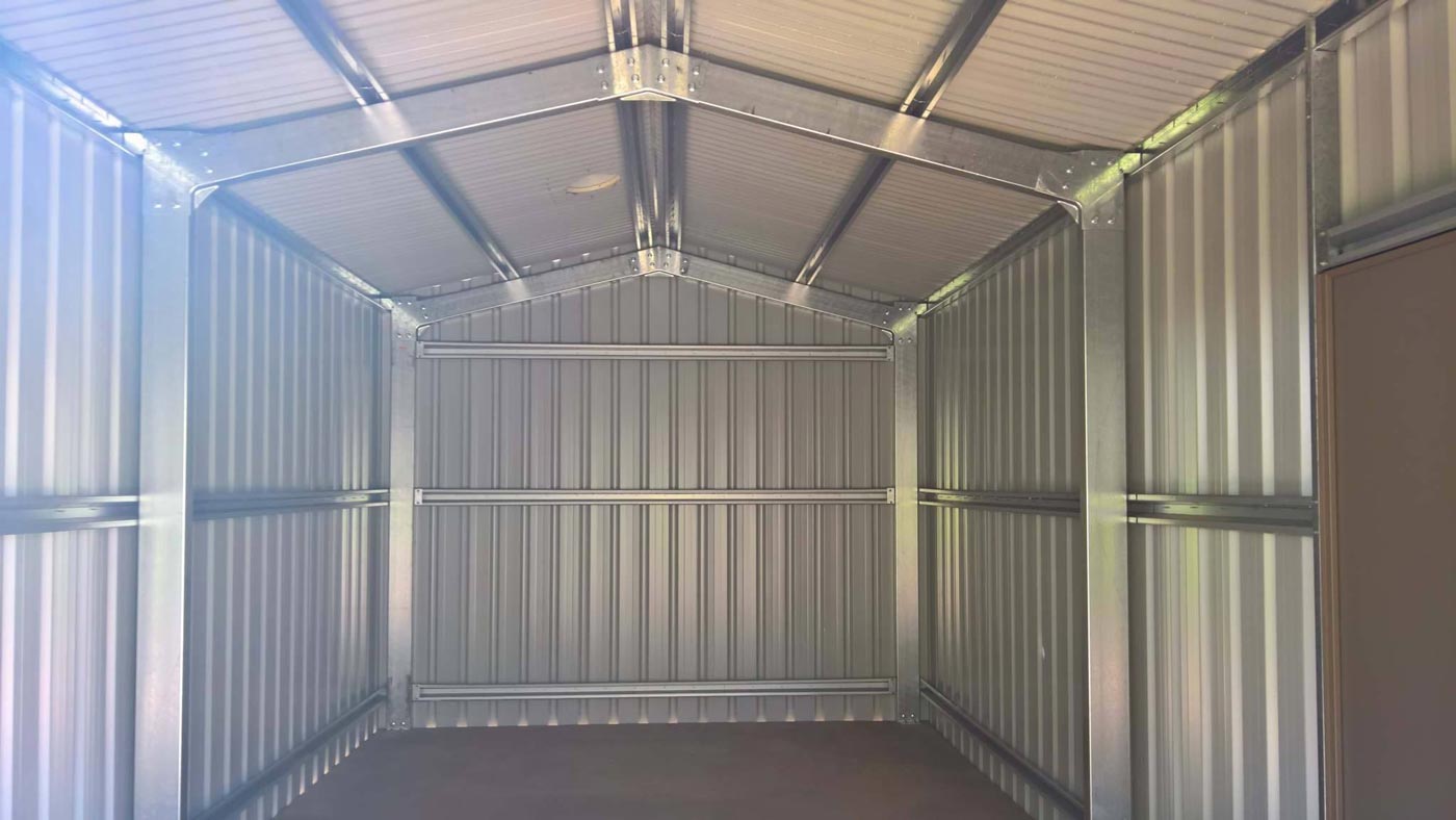 An Empty Metal Garage With A Roof And A Wooden Floor — Alice Sheds & Structures In Ciccone, NT